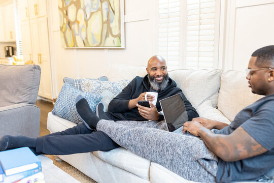 Black gay men have conversations on couch at home