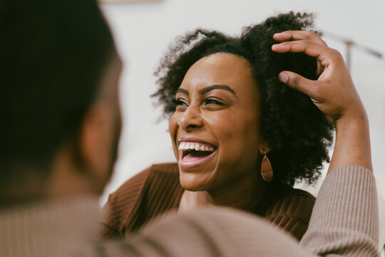 Intimate coversation, black couple at home, man plays with hair, affectionately