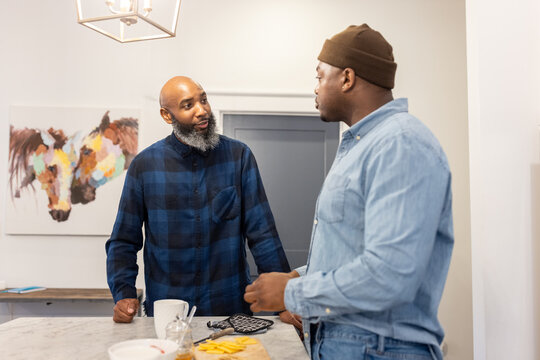 Black gay couple in kitchen at home, playful moment, conversations