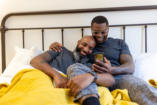 Black couple cuddling in bed at home, LGBTQ pride love connection