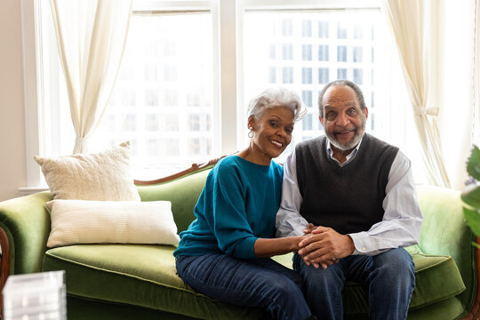 Senior African American couple sitting, smiling, on couch, connections