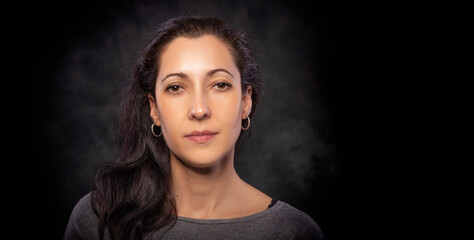 Fototapeta premium Portrait of a young beautiful brunette woman on a dark background.