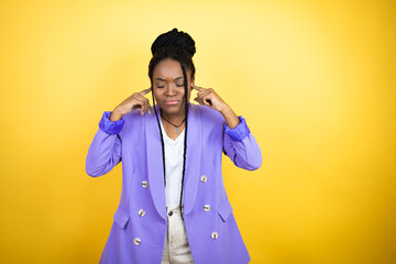 Fototapeta premium Young african american business woman covering ears with fingers with annoyed expression for the noise of loud music. Deaf concept.