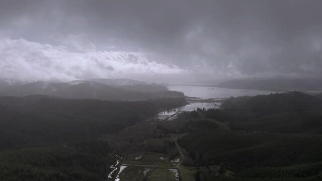 Storm Clouds Gather Over Flooded Coquille Valley With Dense Forest During Winter In Oregon. Aerial Wide Shot