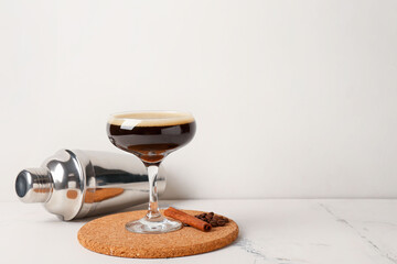 Glass of coffee martini on light background