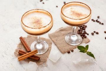 Glasses of coffee martini on light background