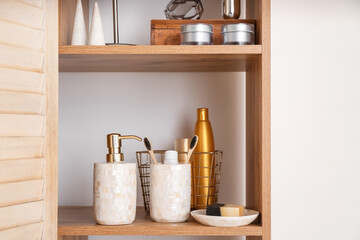 Stylish shelf unit with bath accessories near light wall