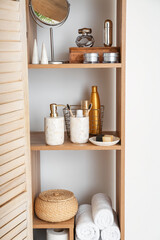 Stylish shelf unit with bath accessories near light wall