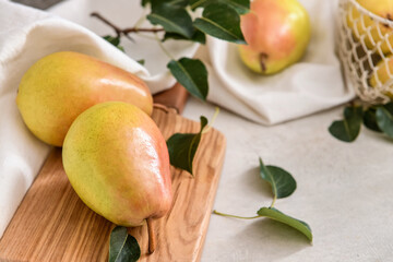 Board with fresh pears on light background