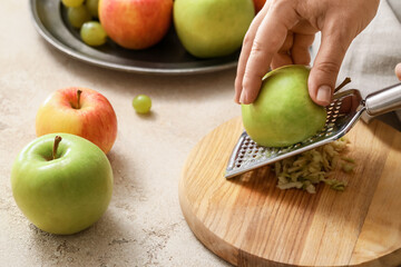 Woman grating apples at table