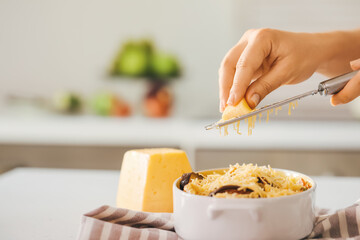 Woman grating cheese in kitchen, closeup
