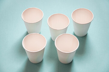 disposable white kraft paper cups stand on blue background