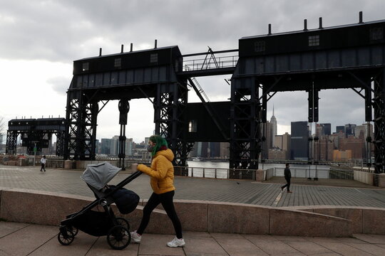 A woman wearing a protective face mask pushes a baby stroller amid the spread of the coronavirus disease (COVID-19) in New York
