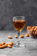 Glass of almond liquor and nuts on dark background