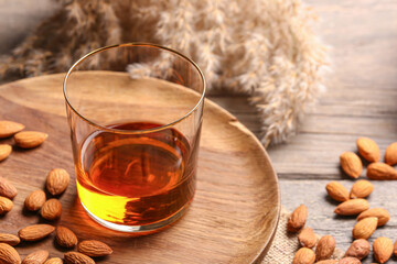 Glass of almond liquor and nuts on wooden background, closeup