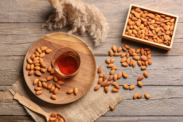 Glass of almond liquor and nuts on wooden background