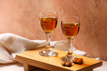 Tray with glasses of almond liquor and nuts on color background