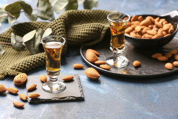Composition with glasses of almond liquor and nuts on color background