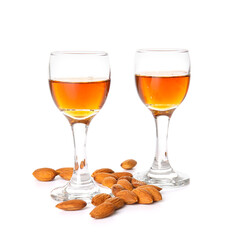 Glasses of almond liquor and nuts on white background