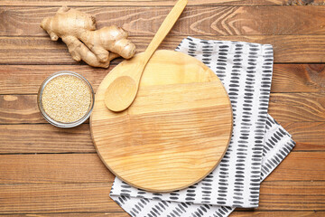 Cutting board, spoon and ginger on wooden background