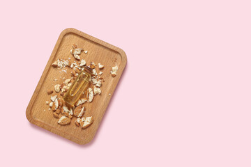 Tray with almond oil and nuts on color background