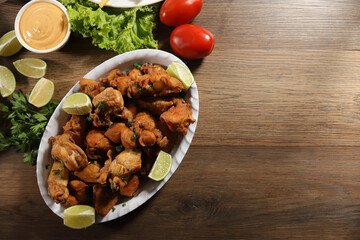 Portion of fried chicken with lemon. Lettuce, green onion, ketchup and mayonnaise