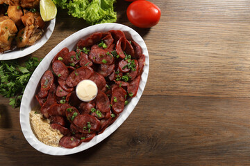 Portion of pepperoni sausage with lemon. Lettuce, green onion, ketchup and mayonnaise