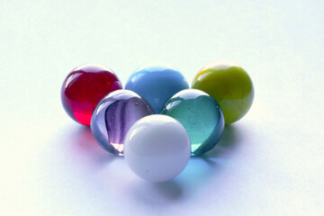 Triangle of 6 coloured marbles on white surface - stock photo