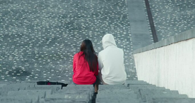 Man and woman sitting at the open-air stadium. Friends spend spare time at the amphitheater outdoors. High quality 4k footage