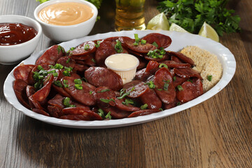 Portion of pepperoni sausage with lemon. Lettuce, green onion, ketchup and mayonnaise