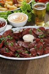 Portion of pepperoni sausage with lemon. Lettuce, green onion, ketchup and mayonnaise