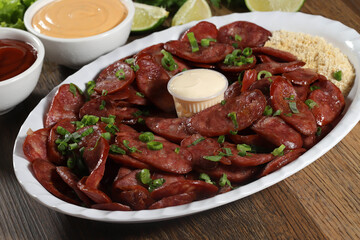 Portion of pepperoni sausage with lemon. Lettuce, green onion, ketchup and mayonnaise