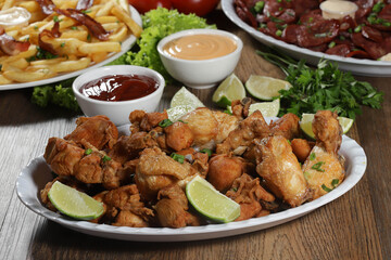 Portion of fried chicken with lemon. Lettuce, green onion, ketchup and mayonnaise