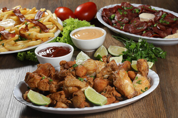 Portion of fried chicken with lemon. Lettuce, green onion, ketchup and mayonnaise