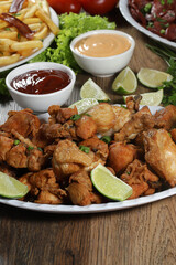 Portion of fried chicken with lemon. Lettuce, green onion, ketchup and mayonnaise