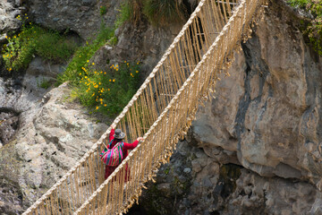 Quechua woman crossing Queshuachaca (Q'eswachaka) rope bridge, one of the last standing Incan handwoven bridges, Quehue, Canas Province, Peru - obrazy, fototapety, plakaty