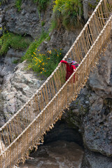 Quechua woman crossing Queshuachaca (Q'eswachaka) rope bridge, one of the last standing Incan...