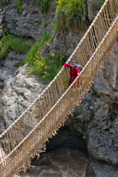 Fototapeta Quechua woman crossing Queshuachaca (Q'eswachaka) rope bridge, one of the last standing Incan handwoven bridges, Quehue, Canas Province, Peru