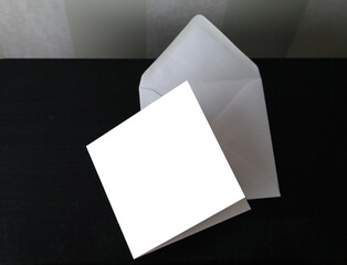 White square postcard and envelope on black table, copy space, selective focus
