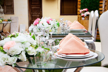  details of glass cups and white plates and pink napkins on top of the plate, all placed on the newlyweds table full of flowers of mixed colors