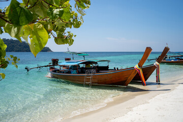 Long-tailed boats moored on the white sands of the blue waters of Andaman. at Koh Lipe island in Satun, Thailand 2021