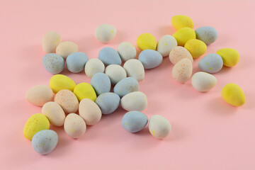 Pastel colored candy Easter eggs in white dessert bowl on pink background