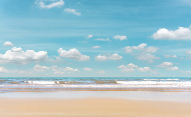 Fototapeta na wymiar Golden sand beach on blue sea under white clouds pastel blue sky