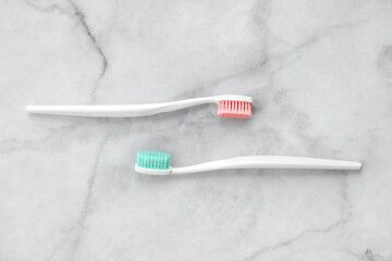 Two toothbrushes with pink and turquoise blue bristle on marble background. Dental and health care concept. Top view, flat lay. - 417508989