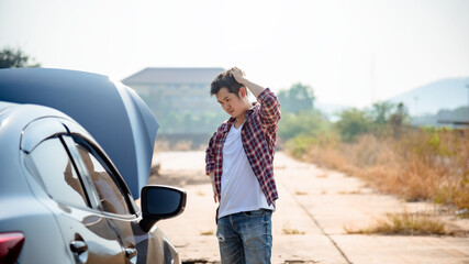 A young man open the bonnet while analyzing the breakdown of the car.