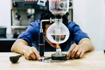 Professional coffee maker - Barista using coffee siphon brewing hot espresso at coffee shop.