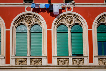 Fototapeta na wymiar Colorful windows in Split courtyard complete with baby clothes drying on a line in the sun