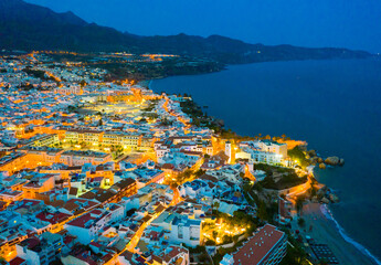 Fototapeta premium Aerial view of illuminated Nerja city at Mediterranean coast, Costa del Sol, Spain