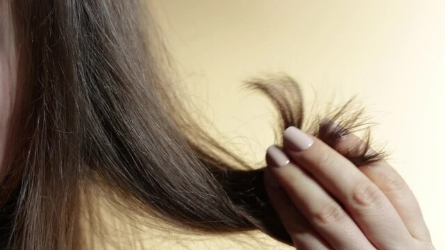 Girl holding her hair with split ends in her hands close-up.