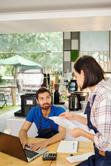 Coffeeshop owners sitting at table and discussing finances, income and